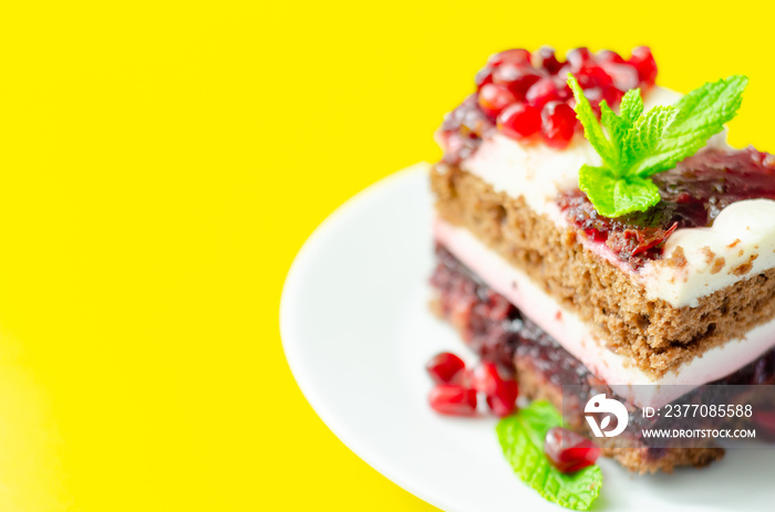 Colorful layered cream chocolate cake with cherry jam and pomegranate