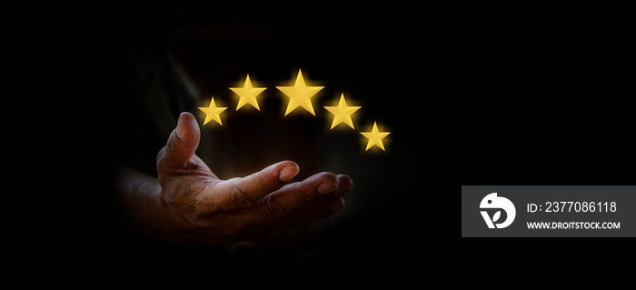 Hand of a man holding five best gold star review scores or satisfaction, quality rating, success symbol on black backgrounds, service rating, vote with like button and positive customer experience.