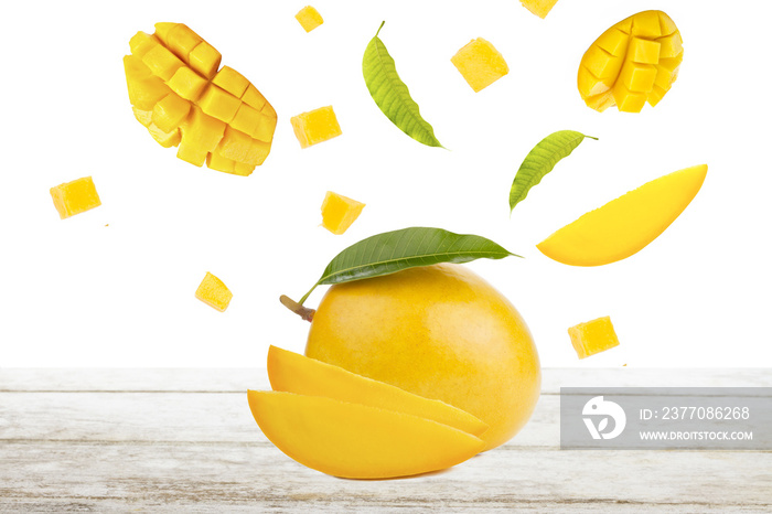 Mango and falling of cut slice with leaf on white wood, isolated background