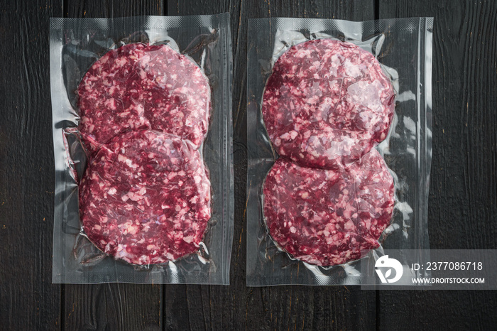 Beef patties in a vacuum packing, on black wooden table background, top view flat lay