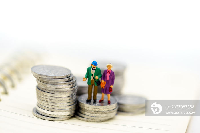 Miniature people: Happy senior couple standing on coins stack, money saving growth. Retirement, emergency plan and Financial Concept.