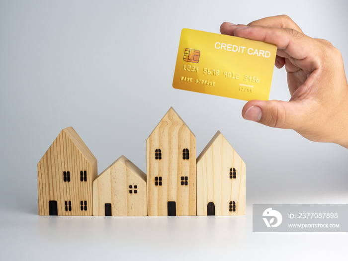 Model wooden house and hand of person holding credit card On a white background. Housing business concept.