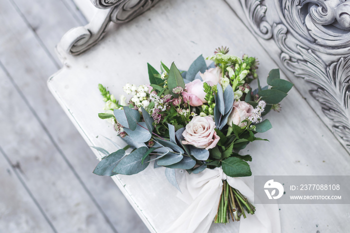 Delicate bride’s bouquet with roses and peonies on a white vinta