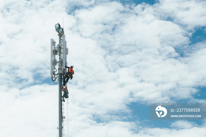 Technician working on communication tower with engineer for digital age development concept