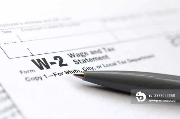 The pen lies on the tax form W-2 Wage and Tax Statement. The time to pay taxes