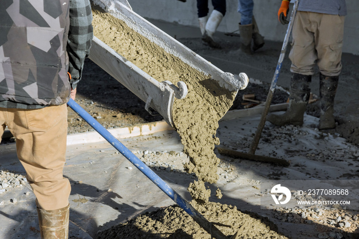 Concrete mixing truck pours out concrete for pavement surrounding new home