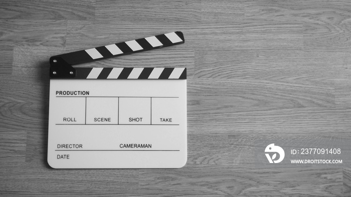 Clapper board or clap board or movie slate use in video production , film, cinema industry. It’s white color on wood background.