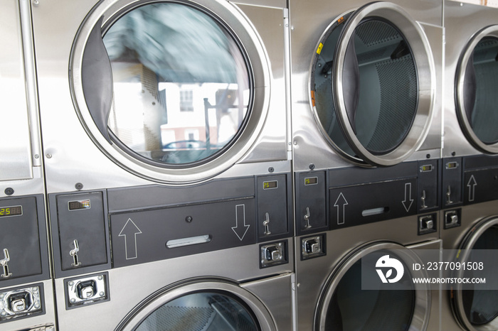 self-service laundry facilities concept - washing machines with clothes inside at laundromat