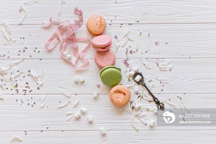 A flat lay of a colorful macarons , spoon on the white texture background