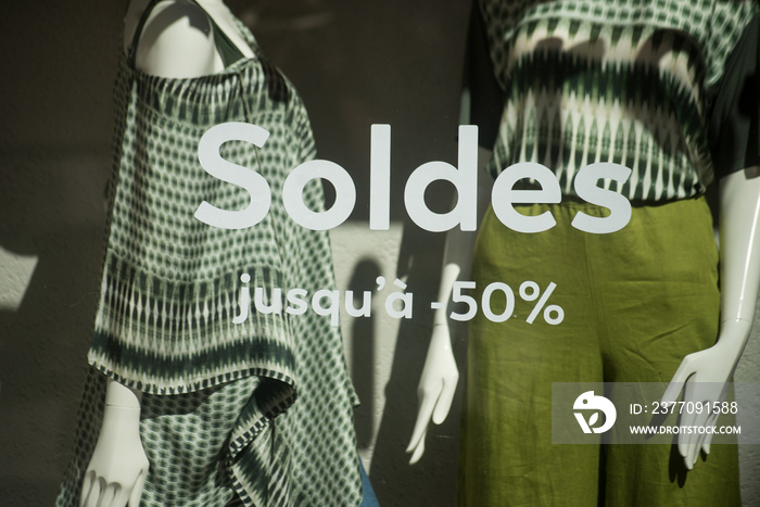 closeup of discount sign  SOLDES jusqu’a 50%  in french,  the traduction of  (sales until 50%) on window in french fashion store showroom on summer clothes background