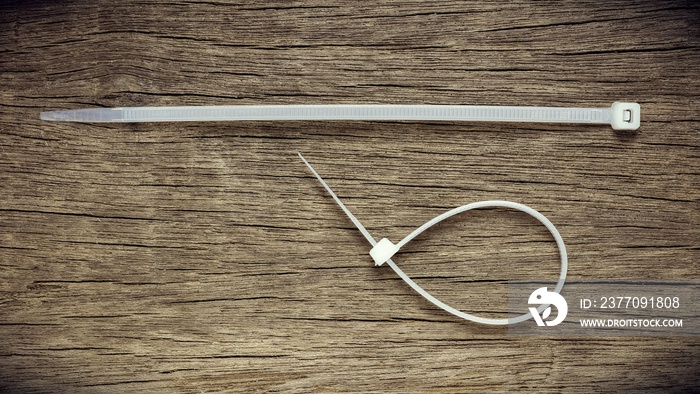 White nylon cable tie on old abandoned wood background.