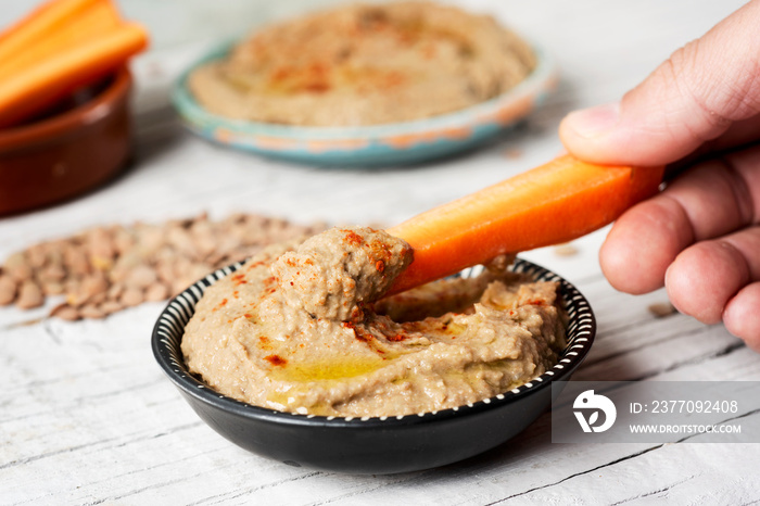 dipping carrot in a homemade lentil hummus