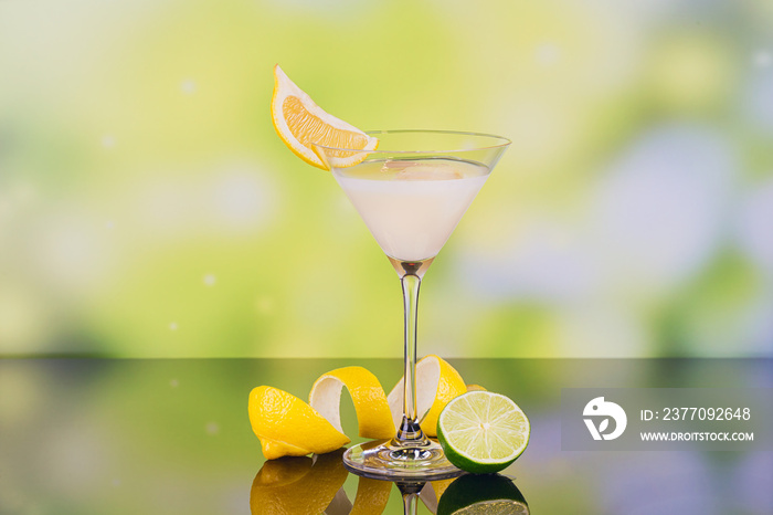 Glasses of cream liqueur with lime and lemon on green background with reflection.