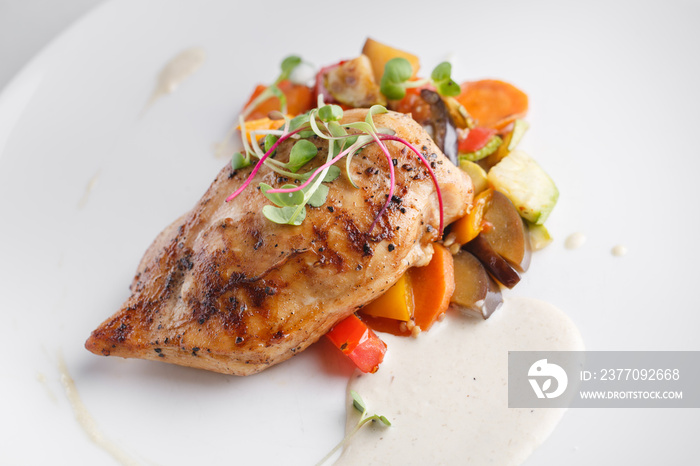 Grilled chicken breast with vegetables. Served on a white plate