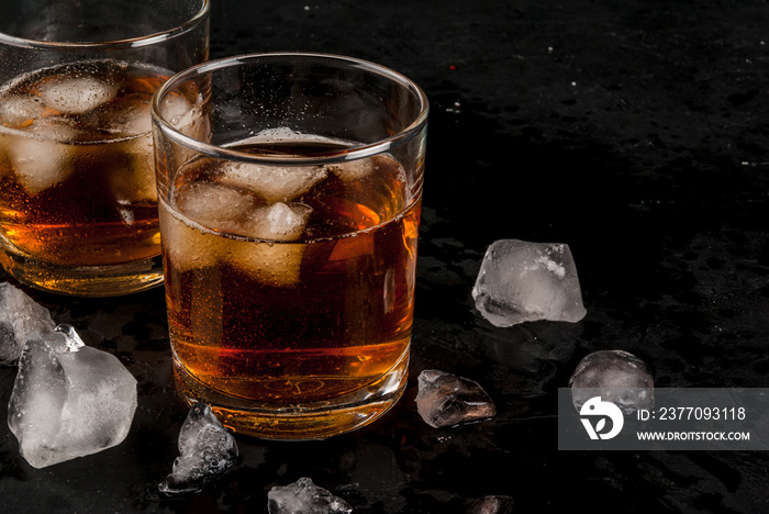 Alcohol whiskey cocktail with cola and ice. On the black table.copy space