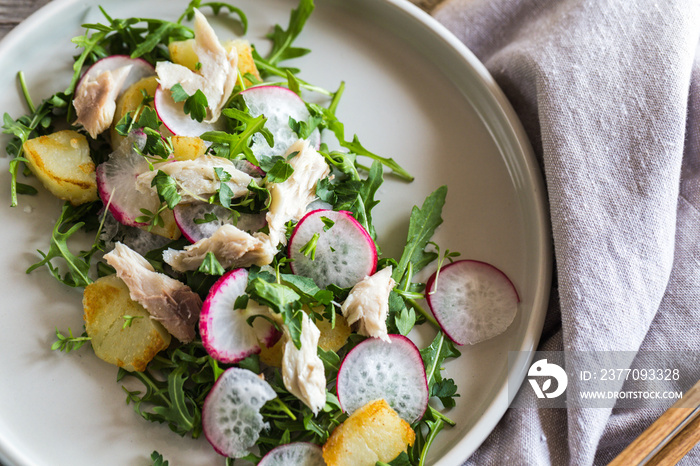Fresh salad with radishes, potatoes, arugula and mackerel or tuna. diet concept