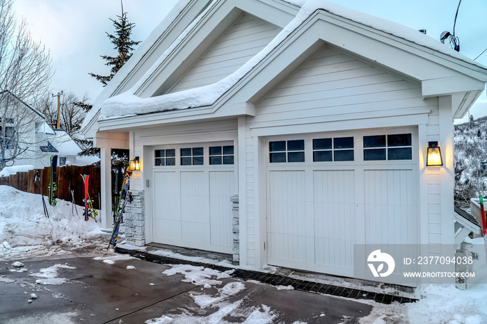 Home with white exterior walls and glass paned garage doors on a mountain town