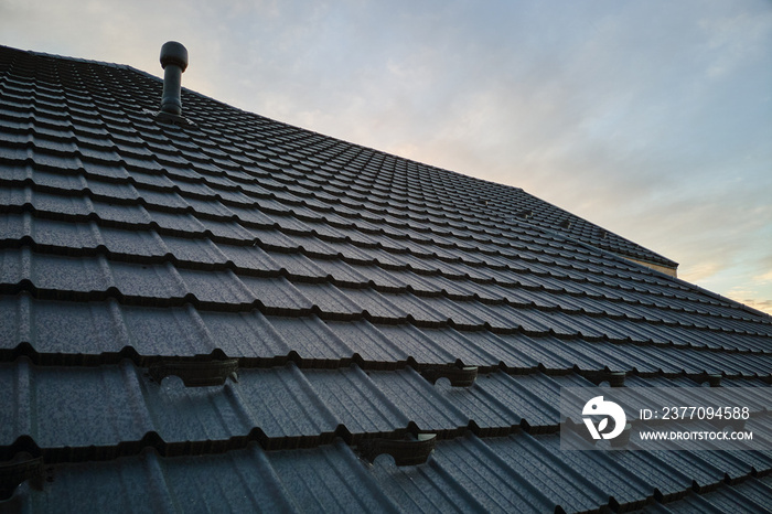 Snow guard for safety in winter on house roof top covered with steel shingles. Tiled covering of building