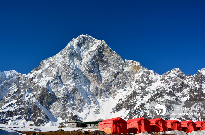 Row of the red tents, way from Cho-La pass to the Everest base camp, Nepal. Magnificent Himalayan mountains on the background.