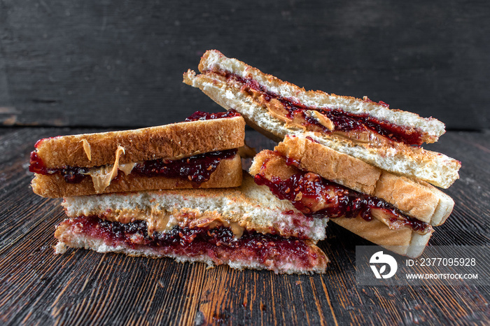 messy peanut butter and jelly sandwiches cut in half in stack