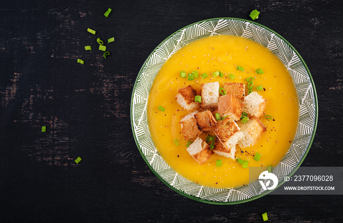 Creamy pumpkin puree soup with croutons, peppers and green onions. Top view, above