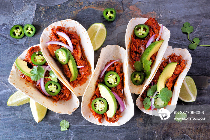 Jack fruit vegan tacos. Overhead view on a dark stone background. Healthy eating, plant-based pulled pork meat substitute.