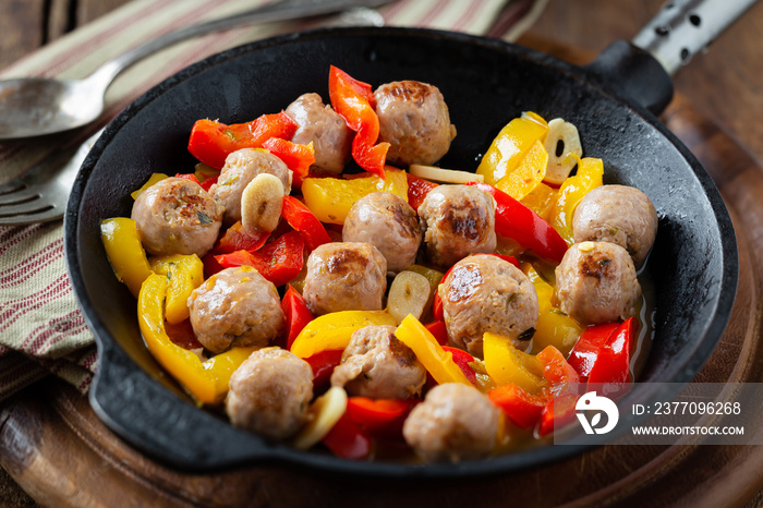 Delicious homemade veal meatballs with red and yellow bell peppers and garlic in a cast iron skillet