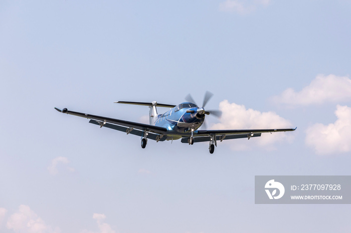 Single-engine blue airplane flying on a sunny day in the blue sky. The plane rises after takeoff.