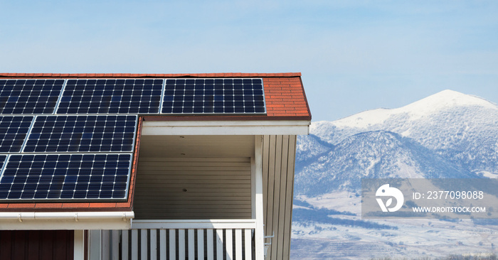 House roof with solar panels on a background os snowy mountains