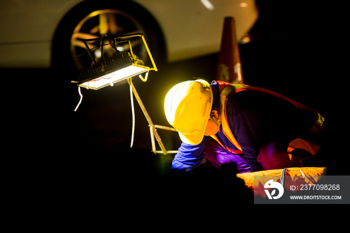 selective focus to spotlight and construction worker is working at night in construction site with black background.