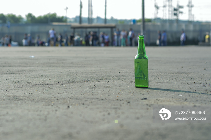 A bottle of beer under an empty square on the background of people waiting for the bus