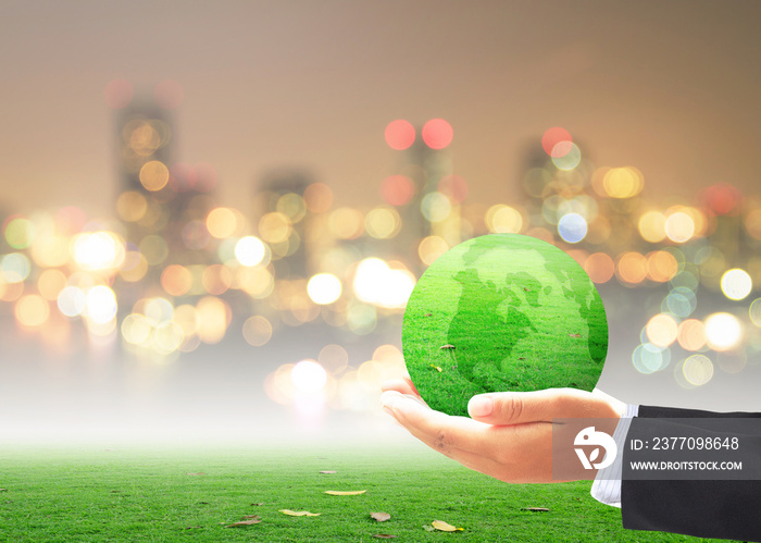 World environment day concept: Businessman hand holding earth globe of grass over blurred city background