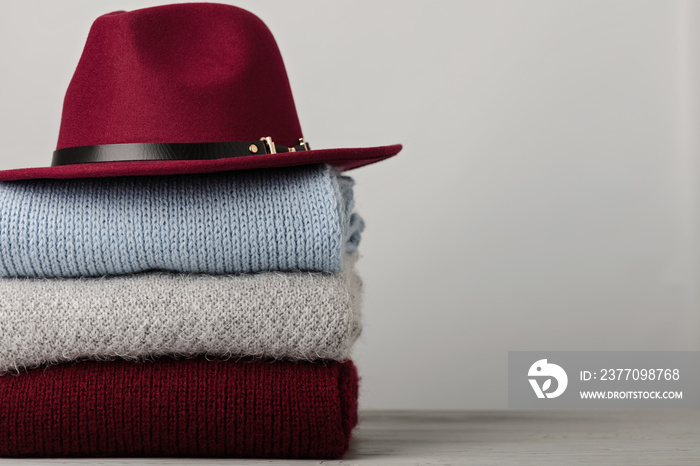 Pile of knitted clothes (sweaters, scarves, pullovers) blue, burgundy, gray colors and hat.