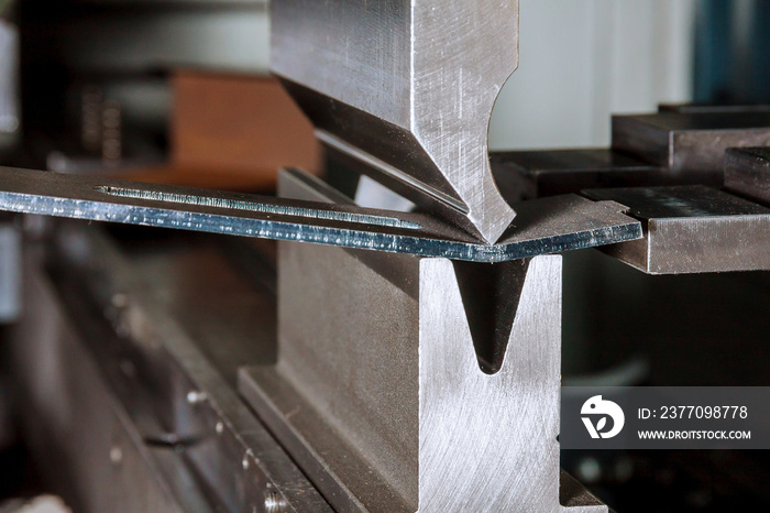 Bending sheet metal on a hydraulic machine at the factory. Bend tools, press brake punch and die. Close-up.