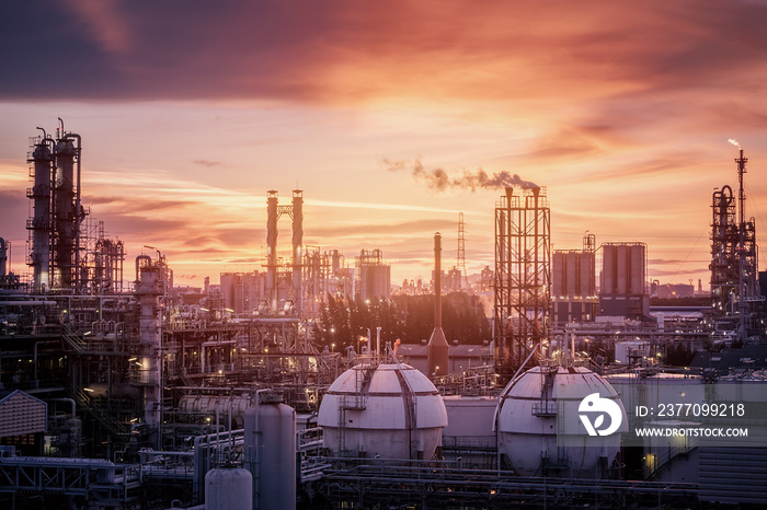 Gas storage sphere tanks in petrochemical industry or oil and gas refinery plant at evening, Manufacturing of petroleum industrial plant with gas column and smoke stacks on sunset sky background