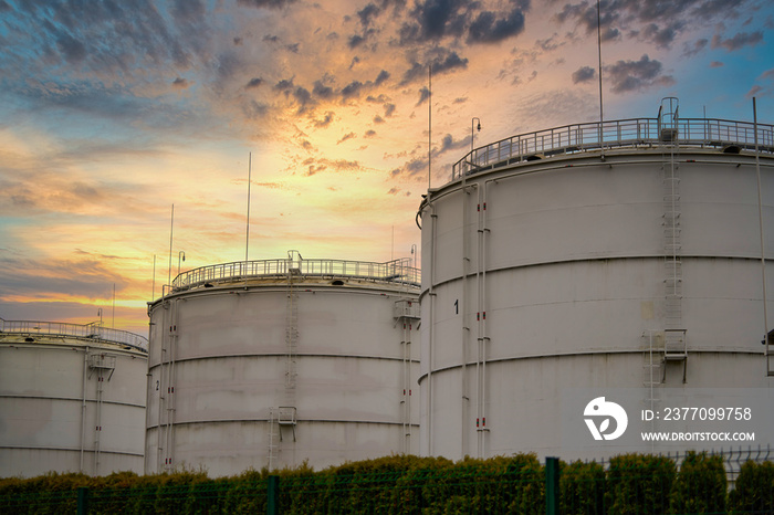 Big industrial oil tanks in a refinery base. Sunset sky