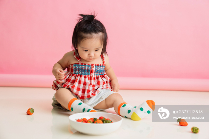 可爱的女宝宝坐在地板上吃草莓