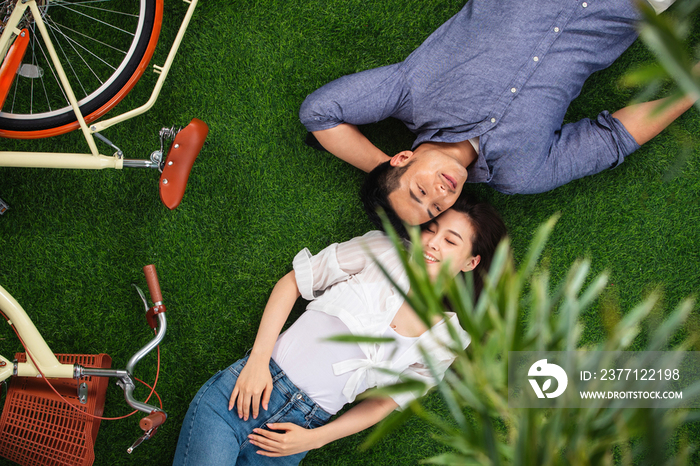 幸福的青年伴侣躺在草地上享受亲密时光