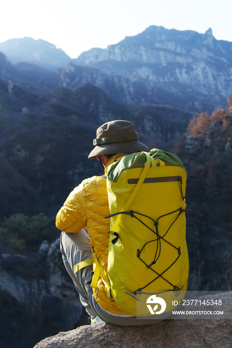 青年登山者坐在山顶俯瞰