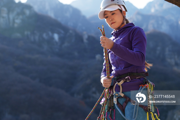 青年女性登山者准备攀岩装备