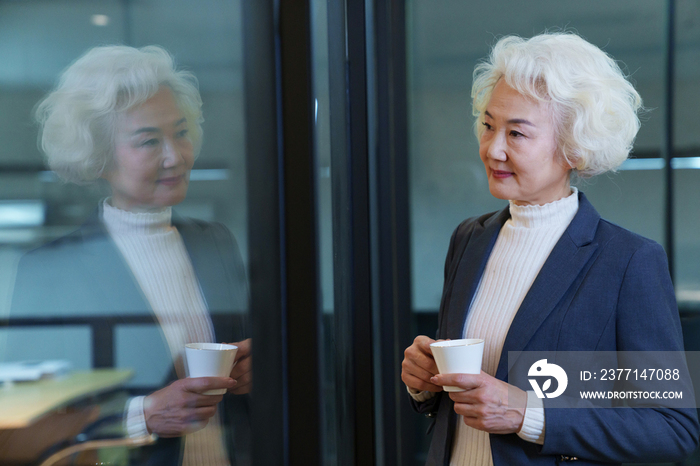 会议室内端着咖啡杯的商务老年女士