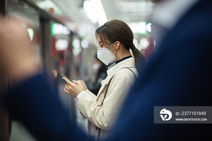 戴口罩的年轻女人站在地铁站台上