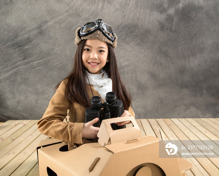 坐在纸飞机里的快乐女孩拿着望远镜