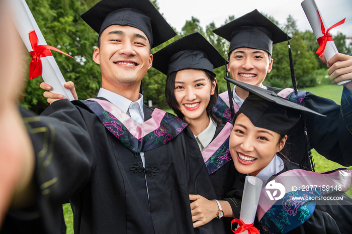 四个身穿学士服的大学生一起自拍