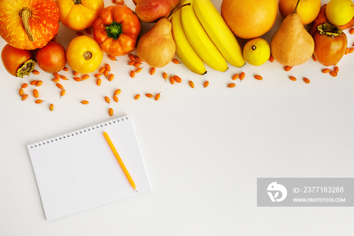 Fresh autumn yellow and orange vegetables and fruits and notebook isolated on white background, top 