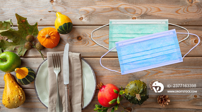 Covid 19 protective mask and thanksgiving pumpkins against wooden background, top view