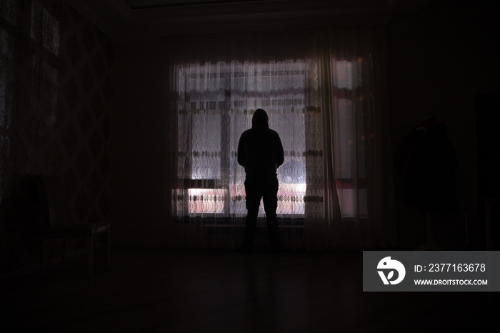 Silhouette of a man standing at a window inside the room. Fantasy picture with old vintage lantern a