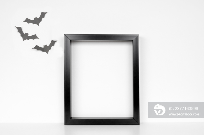 Mock up black frame on a shelf or desk. Halloween concept. Portrait frame against a white wall with 