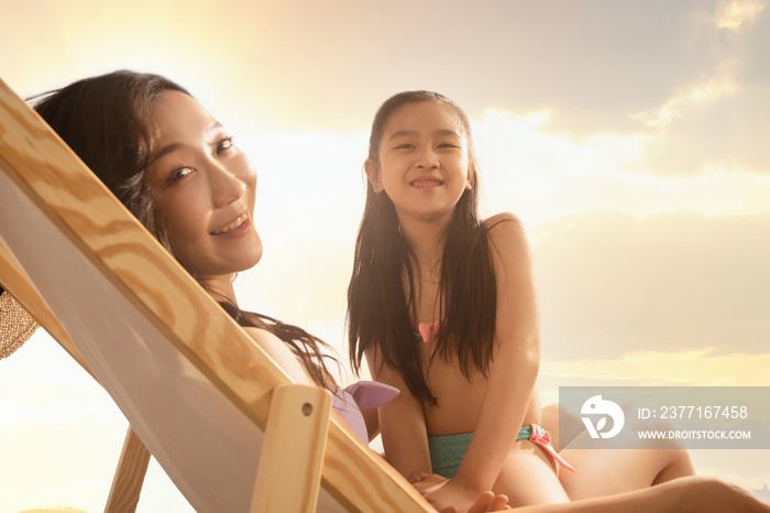 坐在沙滩椅上的年轻妈妈抱着女儿
