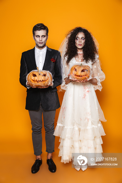 Full length photo of beautiful zombie couple bridegroom and bride wearing wedding outfit and hallowe